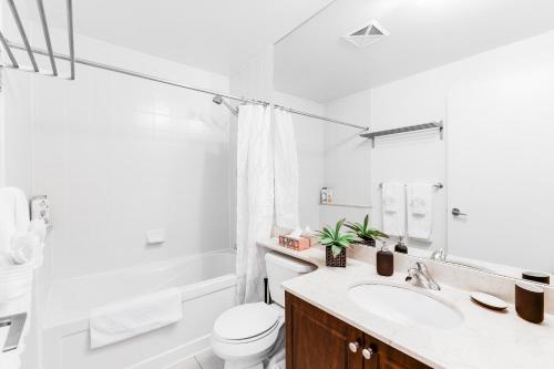 bagno bianco con lavandino e servizi igienici di AOC Suites - High-Rise Condo - City View a Toronto