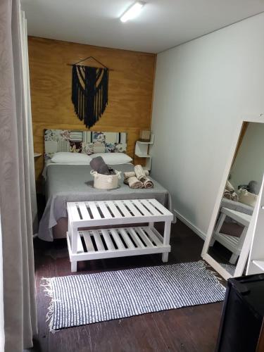 a small bedroom with a bed and a mirror at Moã do Mar Suítes in Guarda do Embaú