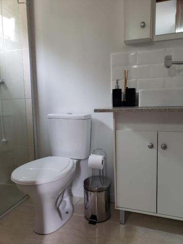 a white bathroom with a toilet and a counter at Moã do Mar Suítes in Guarda do Embaú