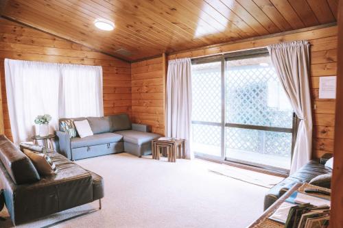 a living room with a couch and a large window at Comfortable Cosy Retreat in Rotorua