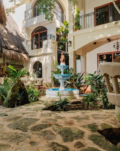 a woman standing next to a fountain in front of a building at Hotel Nojoch che in Cobá