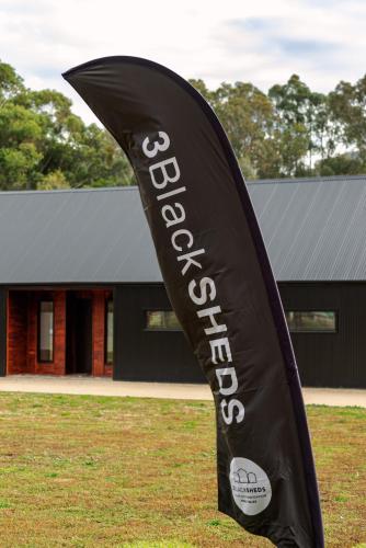 a black flag in the grass in front of a building at 3BlackSHEDS in Whitfield