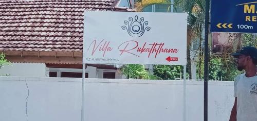 a man standing next to a white fence with a sign at Villa Rukaththana UNAKURUWA in Tangalle