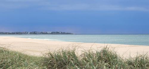 a sandy beach with the ocean and some grass at La Juanita Jose Ignacio in José Ignacio