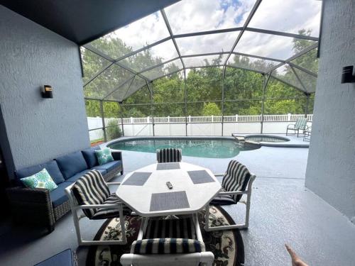 un patio con mesa, sillas y piscina en Luxury Disney Family Villa (5-Bedroom, pool & spa) en Kissimmee