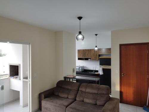 ein Wohnzimmer mit einem Sofa und einer Küche in der Unterkunft Apartamento com garagem e perto das praias. in Palhoça