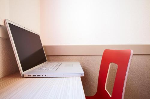 a laptop computer sitting on a desk next to a red chair at Première Classe Paris Ouest - Pont de Suresnes in Suresnes