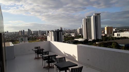 balcone con tavoli, sedie e vista sullo skyline della città di Maravilhoso Apt 109 Home Service próximo Shopping Partage e Rodoviária a Campina Grande