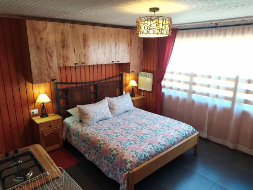 a bedroom with a bed and a window and a chandelier at Departamentos Turísticos J&M en Dichato in Dichato
