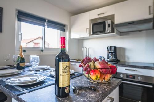 Uma garrafa de vinho e uma taça de fruta no balcão da cozinha. em Le SAPHIR - 20min from Paris & CDG Airport - 2 bathrooms - 2 Desks em Drancy