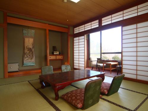 a dining room with a wooden table and chairs at Guest Room Furusatomura Kogeikan in Omachi