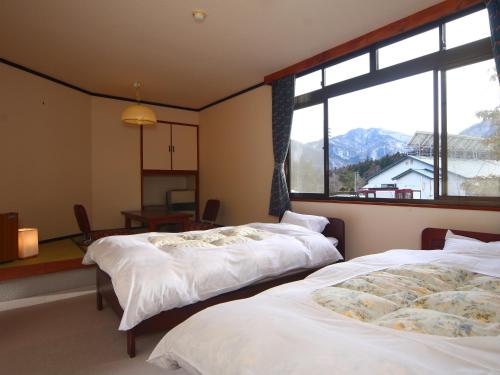 大町市にあるゲストルーム　ふる里村工芸館の大きな窓付きの客室で、ベッド2台が備わります。