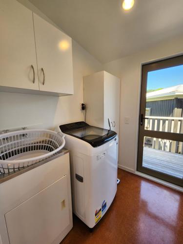 a kitchen with a sink and a dishwasher and a window at Easy Days Hahei in Hahei