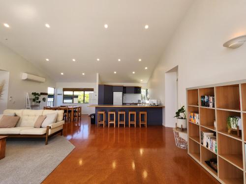 a large living room with a couch and a kitchen at Easy Days Hahei in Hahei