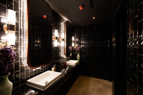 a black bathroom with a sink and a mirror at The Ember Hotel in Bangkok