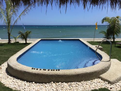 a swimming pool in a stone bowl next to the ocean at BambooBeachVilla1 AC New OCEANFRONT POOL sunsetview garden kitchen SATELLITE STARLINK WI-FI in Dimiao