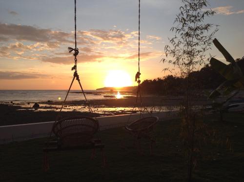 a swing at the beach with the sunset in the background at BambooBeachVilla1 AC New OCEANFRONT POOL sunsetview garden kitchen SATELLITE STARLINK WI-FI in Dimiao