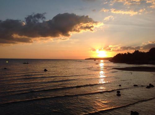 a sunset on the beach with people in the water at BambooBeachVilla1 AC New OCEANFRONT POOL sunsetview garden kitchen SATELLITE STARLINK WI-FI in Dimiao