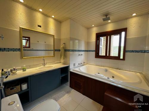 y baño con bañera, aseo y lavamanos. en Casa de praia no Rosa - vista para Lagoa de Ibiraquera, en Imbituba