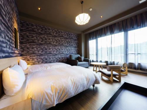 a bedroom with a white bed and a brick wall at Grandvrio Hotel Beppuwan Wakura - ROUTE INN HOTELS - in Beppu