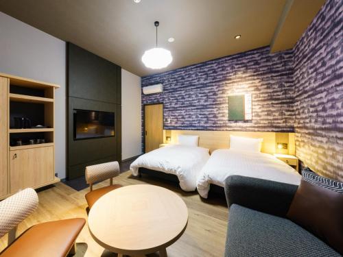 a hotel room with two beds and a table at Grandvrio Hotel Beppuwan Wakura - ROUTE INN HOTELS - in Beppu