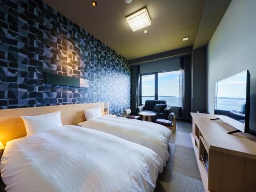 a hotel room with two beds and a flat screen tv at Grandvrio Hotel Beppuwan Wakura - ROUTE INN HOTELS - in Beppu