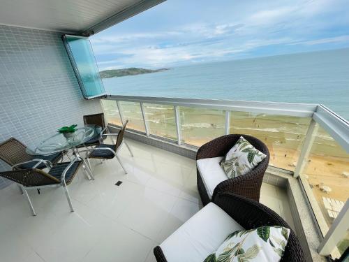 een balkon met een tafel en stoelen en de oceaan bij praia do morro Guarapari,beira mar topíssimo apartamento in Guarapari