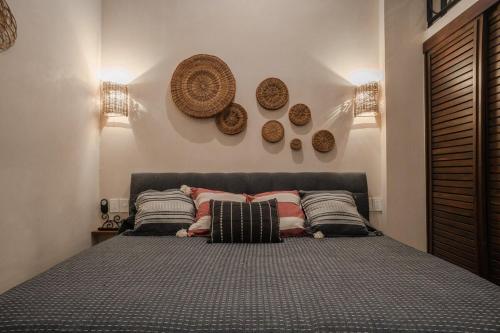 een slaapkamer met een bed met kussens en borden aan de muur bij Casa Luz Downtown Apartments in Tulum in Tulum