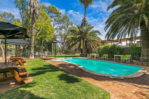 a swimming pool in a yard with tables and chairs at Erldunda Desert Oaks Resort in Erldunda