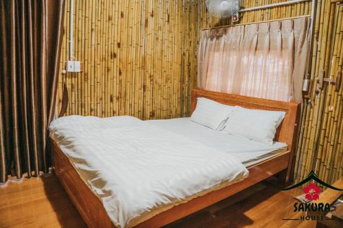 a bed with white sheets and pillows in a room at SAKURA House - Vườn Đào in Mộc Châu