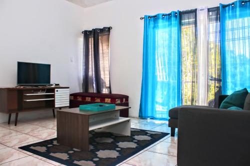 a living room with blue curtains and a tv at Crystoural Apartment Liguanea Sovereign Apt - 2 Bedrooms, 3 Beds, Host 4 Guest- Kingston! in Kingston