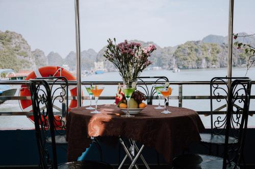 a table with a vase of flowers and drinks on a balcony at Cat Ba Bay Cruises in Cat Ba