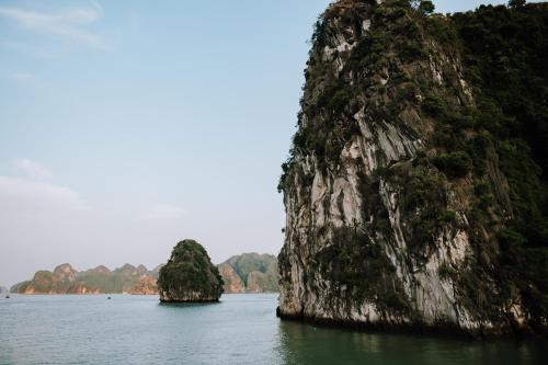 a large rock formation in the water next to a mountain at Cat Ba Bay Cruises in Cat Ba