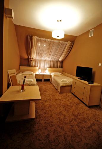 a hotel room with two beds and a television at Hotel Hibiskus in Boguchwała