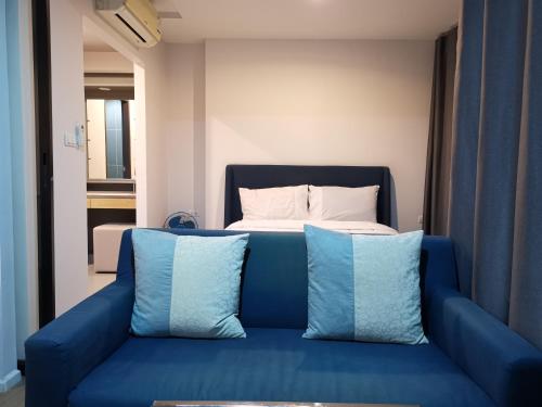 a blue couch with two pillows in front of a bed at 4 Floor - Centrio Condominium near Shopping Malls and Andamanda Water Park in Phuket Town
