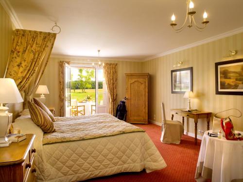 a bedroom with a bed and a table and a window at Logis Le Fleuray in Cangey