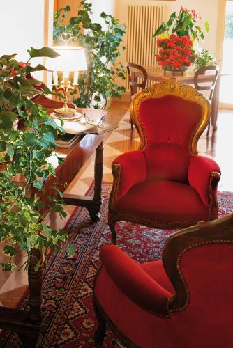 a living room with a red chair and a table at Villa Busta Hotel in Montebelluna