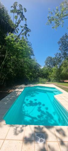 a blue swimming pool with trees in the background at Cabaña Oma in Puerto Iguazú