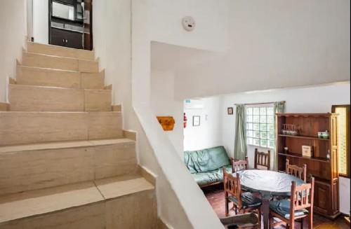 sala de estar con escaleras, mesa y sillas en Dúplex Complejo Marina I - Zona Centro en Villa Gesell