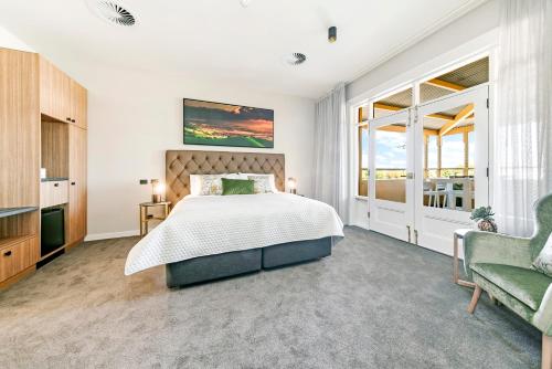 a bedroom with a bed and a large window at The Tanunda Club Guest Suites in Tanunda