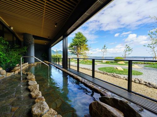 uma grande piscina de água numa casa com uma grande janela em Grandvrio Hotel Beppuwan Wakura - ROUTE INN HOTELS - em Beppu