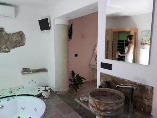 a woman in a bathroom with a sink and a tub at Il Daviduccio Suite in Siracusa