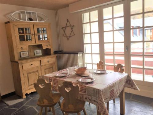 une cuisine avec une table, des chaises et un tissu de table dans l'établissement Appartement T2 pour 4 avec balcon, Wi-Fi gratuit, proche des pistes et équipements complets - FR-1-457-220, à Saint-Lary-Soulan
