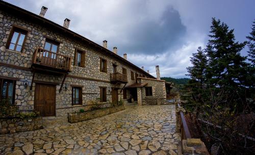 a large stone building with a stone driveway at Pigi Tarlampa Hotel in Ano Trikala