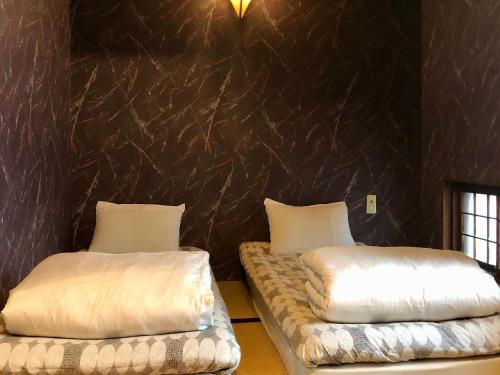 a room with two beds with white pillows at Hostel Yume-Nomad Kobe in Kobe