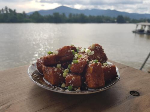 a plate of food on a table next to a body of water at The Hideaway in Kampot