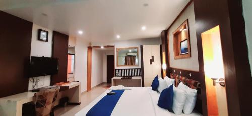 a hotel room with a large bed with blue pillows at Hotel Kosala Vijayawada in Vijayawāda