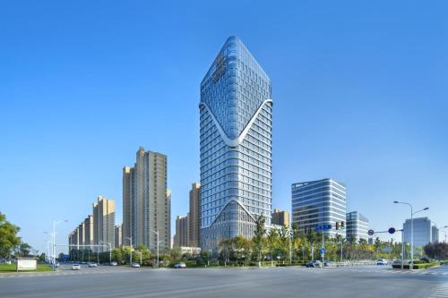 a tall glass building in a city with tall buildings at The Barony Jinan East in Jinan
