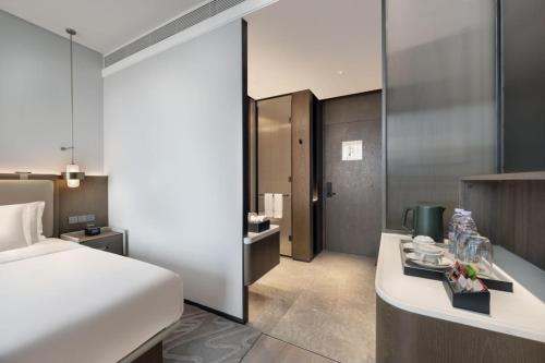 a hotel room with a bed and a desk with cups at The Barony Jinan East in Jinan