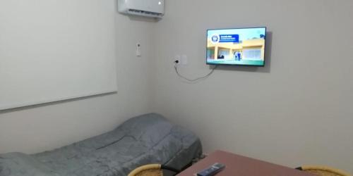 Habitación con cama y TV en la pared. en Departamento DYD JUJUY en San Rafael
